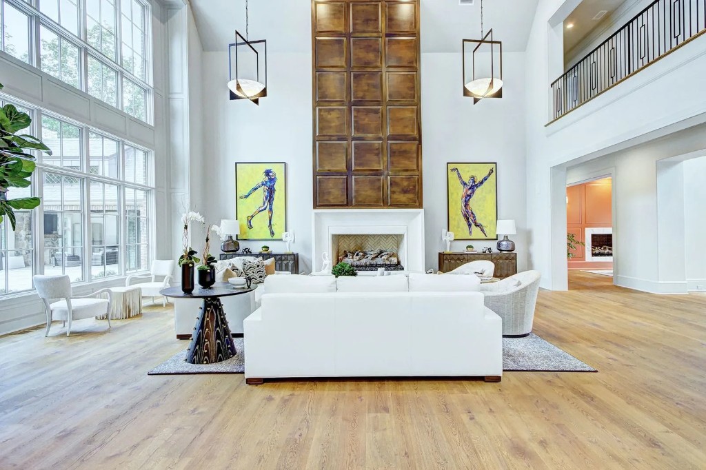 Double-height living room with wood-paneled fireplace and gallery art
